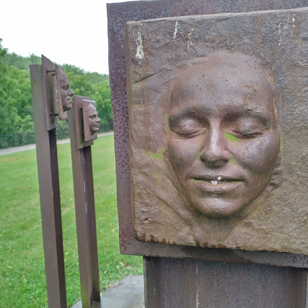 Bas-Relief of faces mounted on poles in a sculpture park
